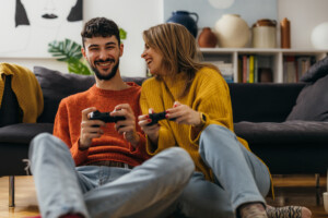 Junges Pärchen sitzt im Wohnzimmer und spielt gemeinsam ein Videospiel